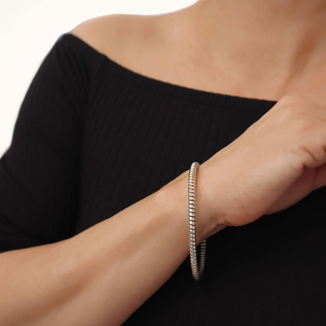 UK 925 sterling silver bracelet with a twisted cable rope design on a woman's wrist against a black background