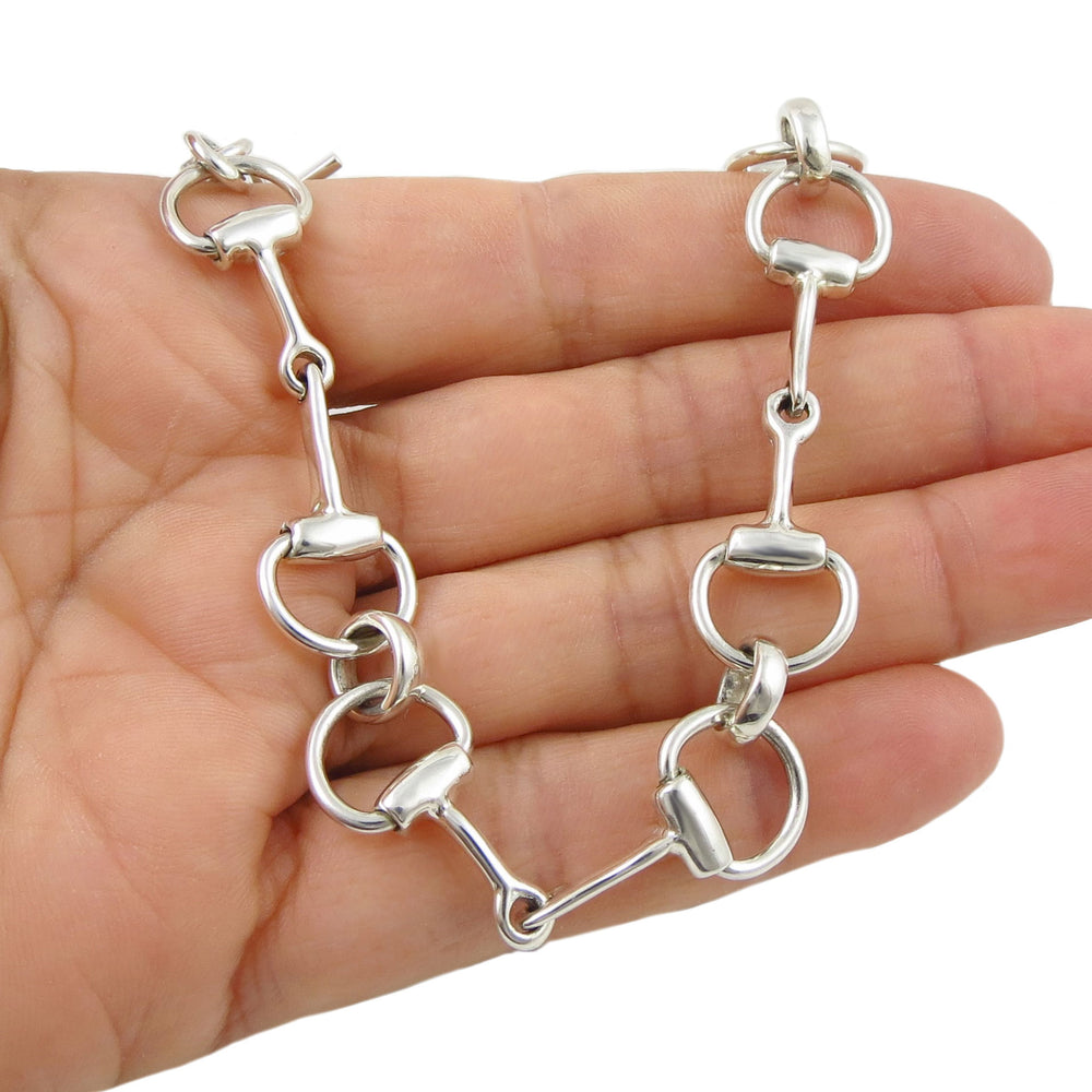 Silver snafflebit bracelet held in a hand on a white background