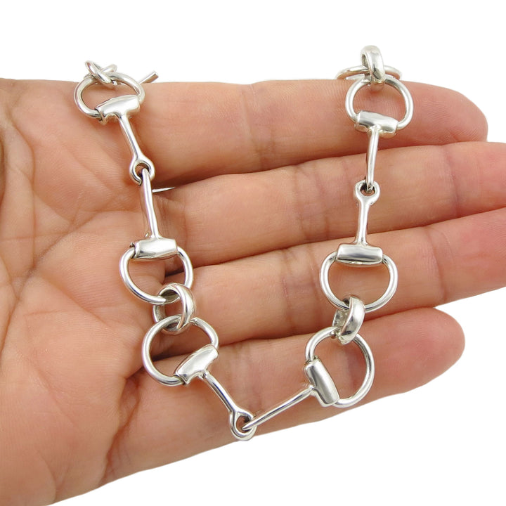 Silver snafflebit bracelet held in a hand on a white background