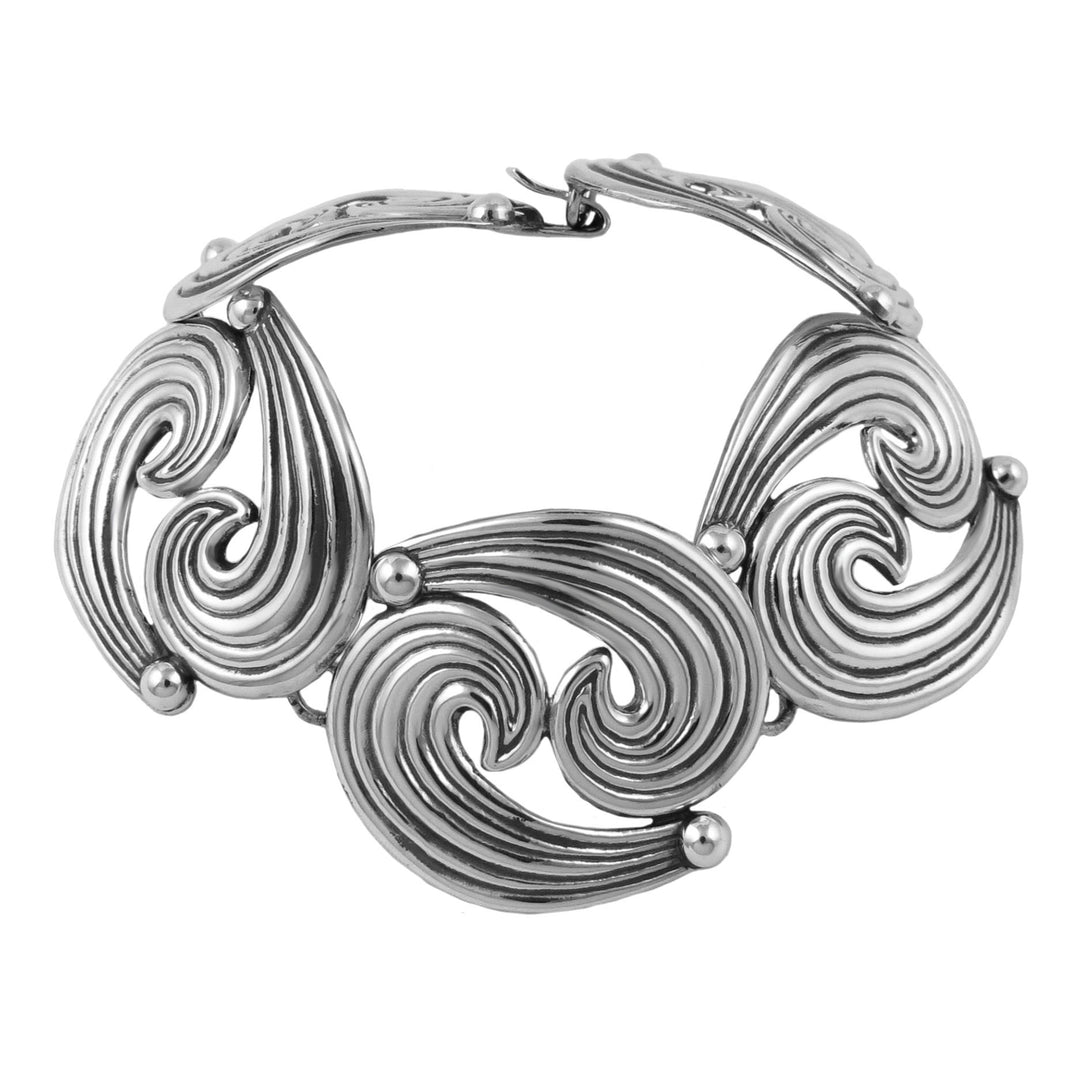 Sterling silver bracelet with intricate spiral wave design on a white background