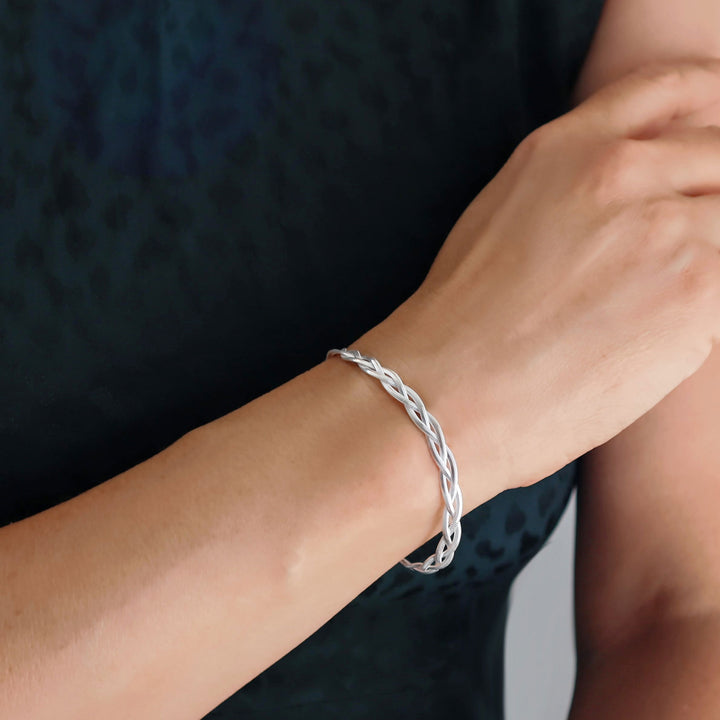 Silver braided snake chain bracelet on a wrist against a dark background