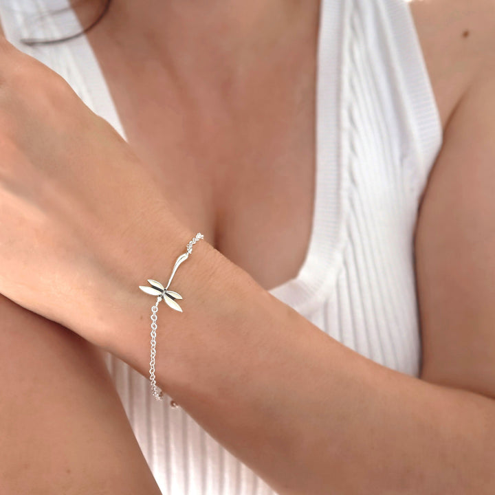 Silver bracelet with a dragonfly design on a person's wrist against a white background