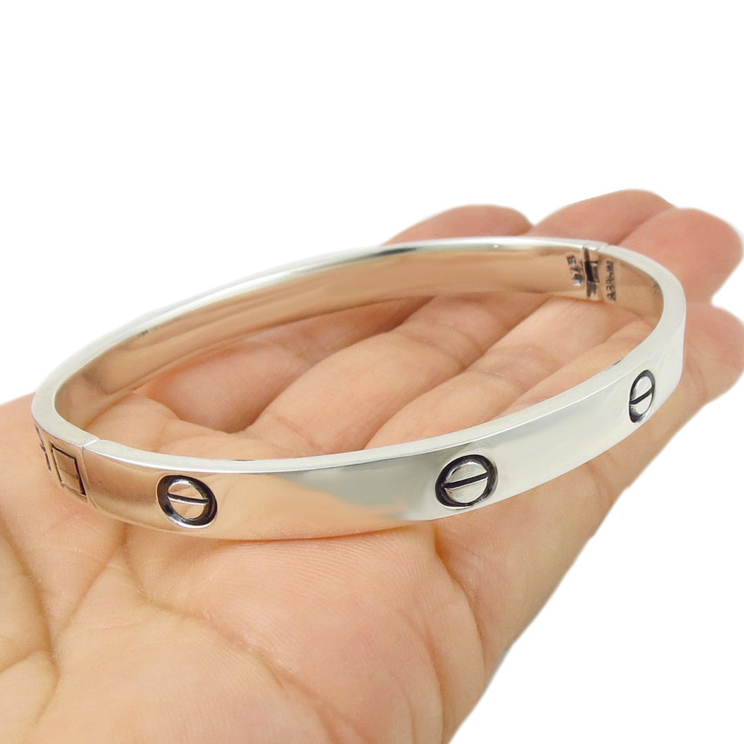 Silver bracelet with engraved rivet screw shapes on a hand against a white background