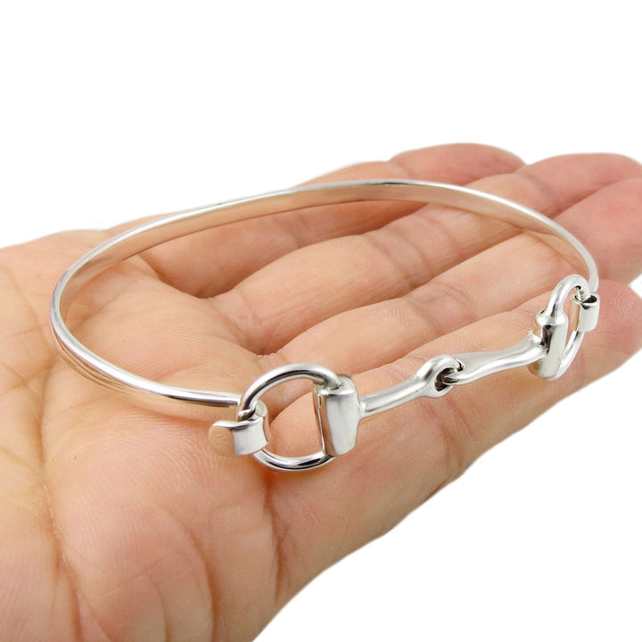 Silver hore snaffle bit bracelet on a hand against a white background