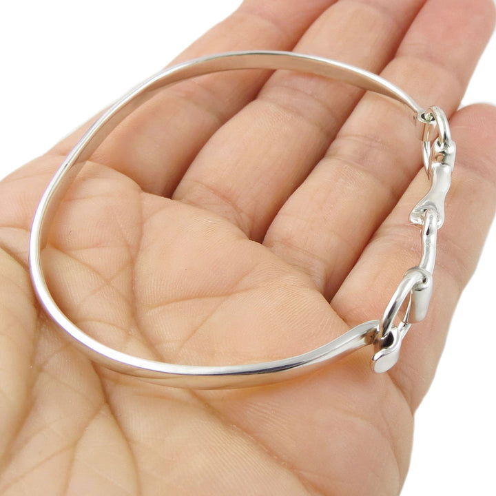 Silver horsebit bracelet on a hand with a white background