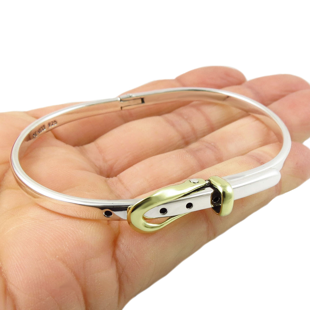 Silver and gold buckle bracelet on a hand with a white background