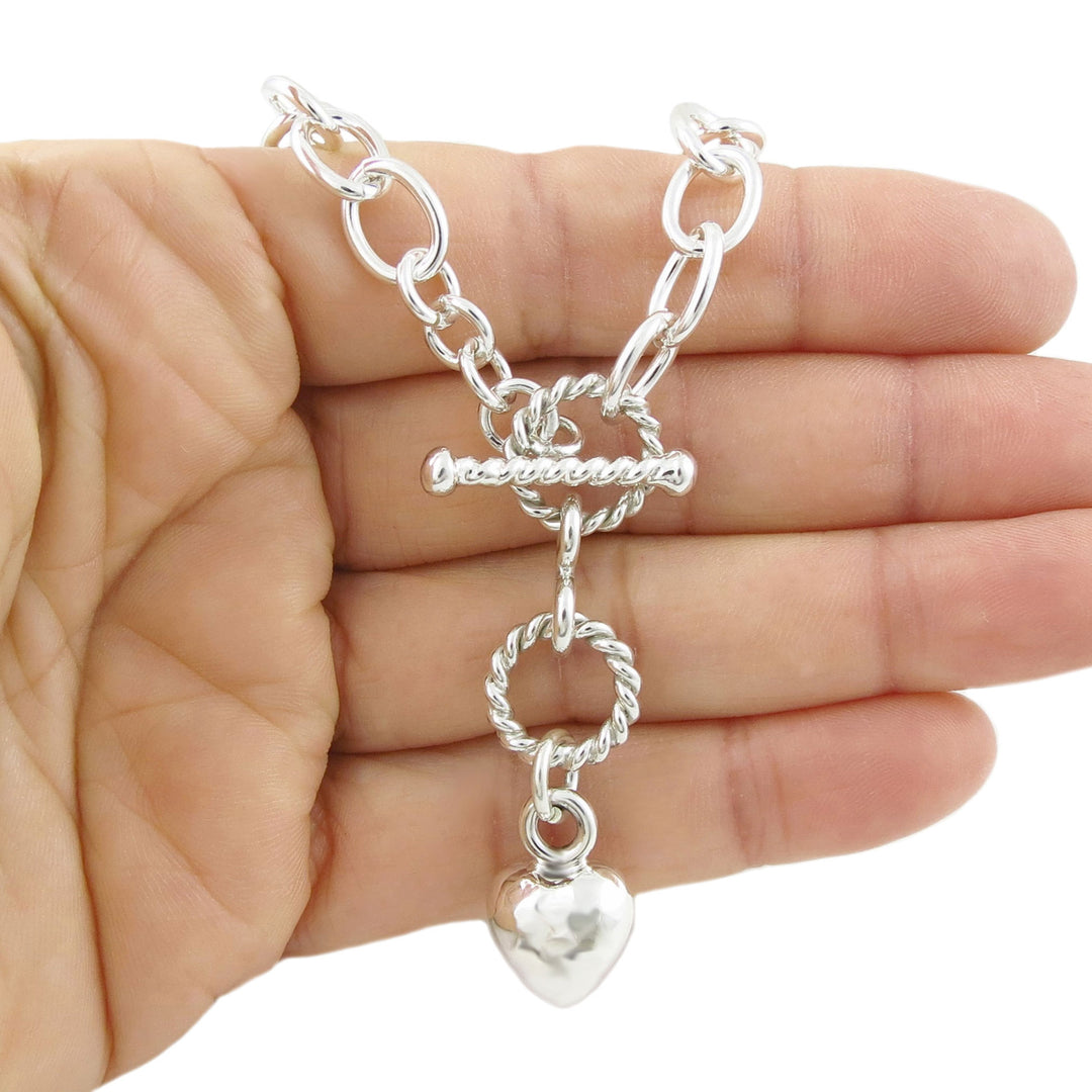 UK 925 sterling silver chain bracelet with puffy heart charm held in a hand on a white background