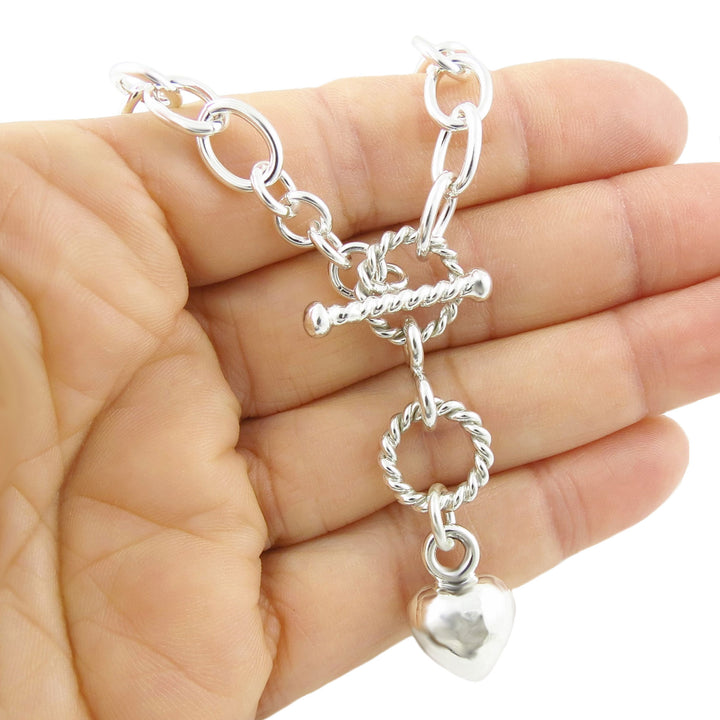 925 sterling silver chain bracelet with a puffed heart charm held in a hand against a white background