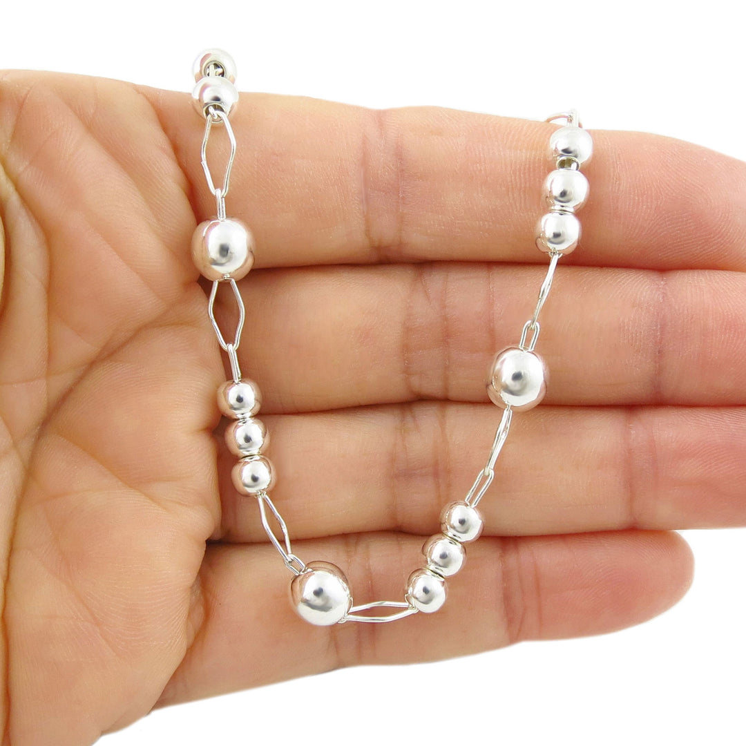 Handmade UK sterling 925 silver beaded bracelet with a polished finish on a hand against a white background