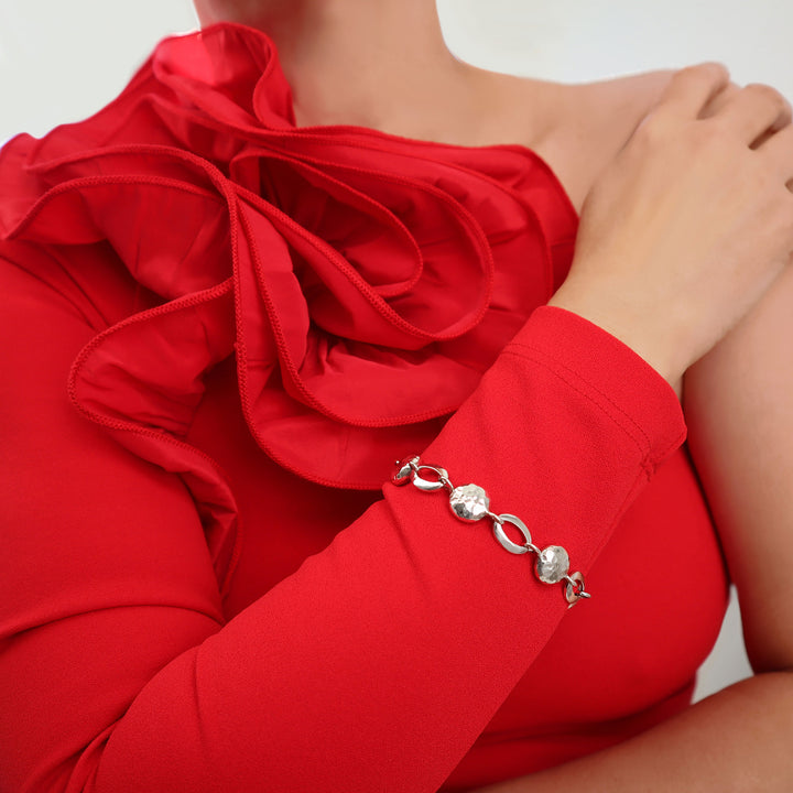 A woman in a red dress wearing a unique handmade sterling 925 silver UK hallmarked bracelet feaaturing round and oval links.