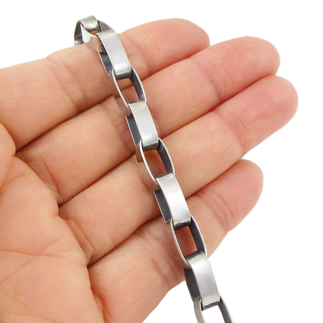 Long modern UK sterling silver oval link chain bracelet held in a hand against a white background
