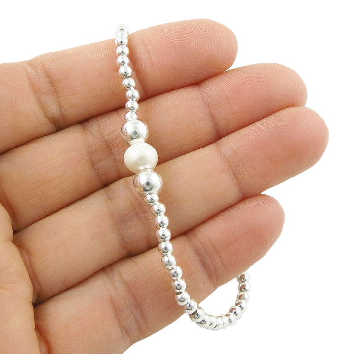 925 sterling Silver beaded stretch bracelet with a white pearl held in a hand on a white background