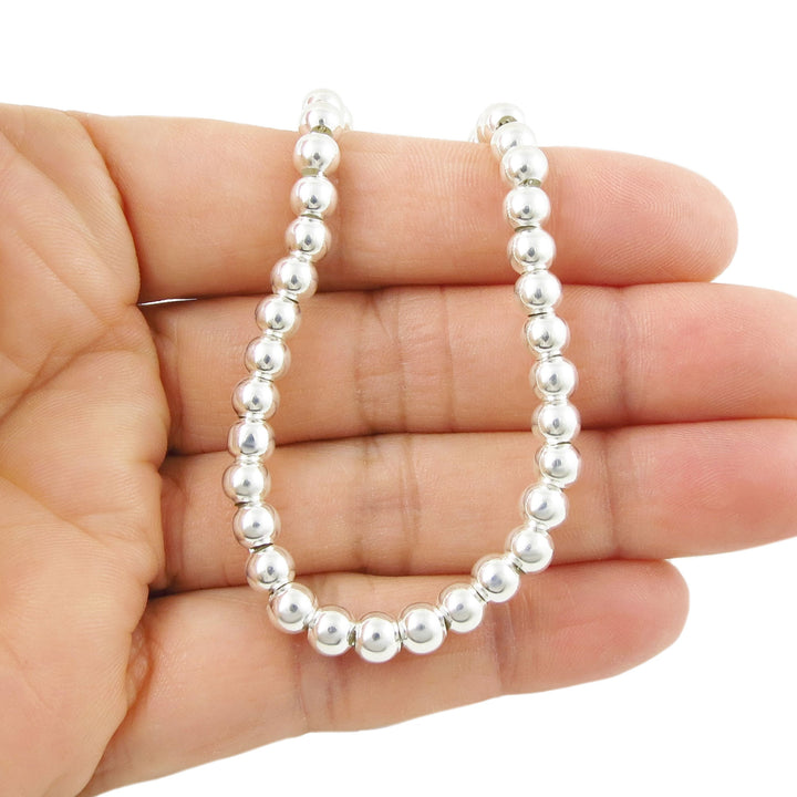 A large UK 925 sterling silver wide beaded bracelet held in a person's hand on a white background. 