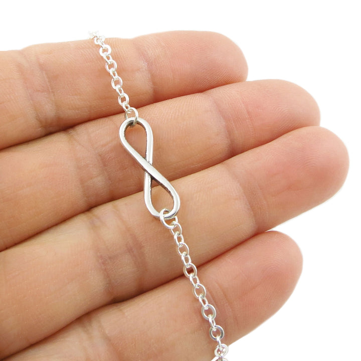 A large figure of eight infinity symbol chain bracelet in sterling silver held in a person's hand.
