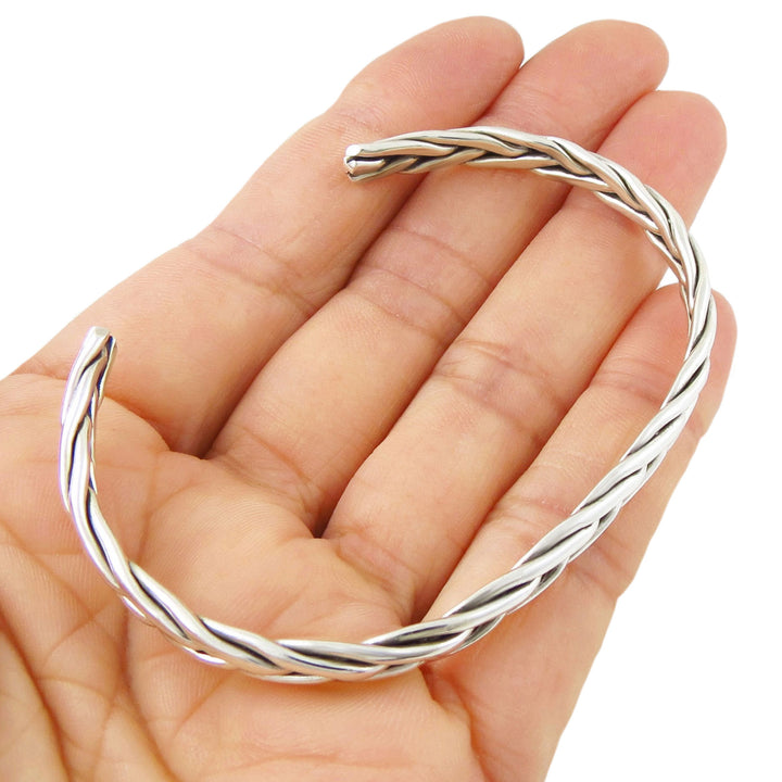 SSterling 925 silver braided bracelet held in a hand on a white background