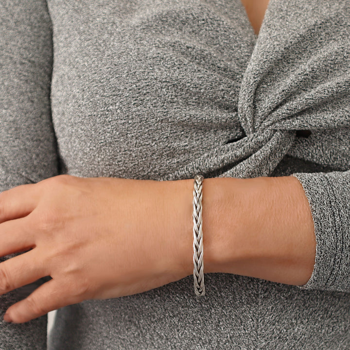 Woman wearing a braided UK 925 sterling silver bracelet on a gray background