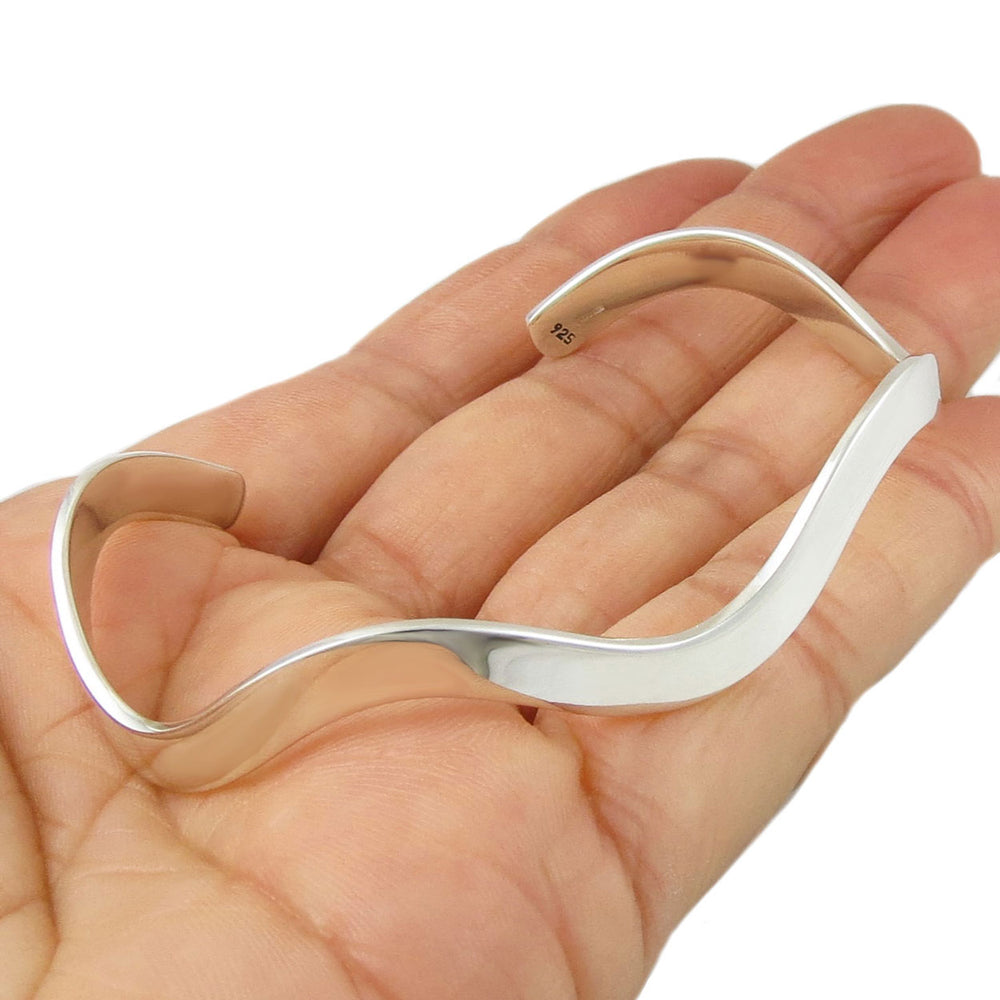 Sterling 925 silver curved bracelet cuff on a hand against a white background