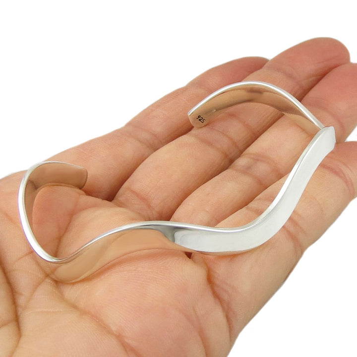 Sterling 925 silver curved bracelet cuff on a hand against a white background