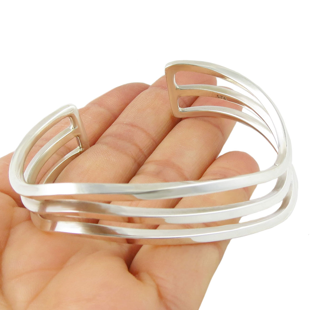 Minimalist silver bracelet on a hand against a white background