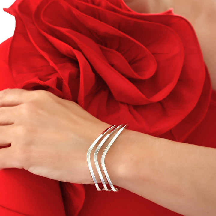 Minimalist silver jewellery bracelet on a wrist with a red fabric background