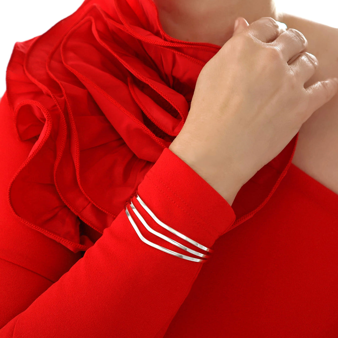 A woman in a red dress wearing a unique handmade cuff bracelet featuring three strands in solid sterling silver. 