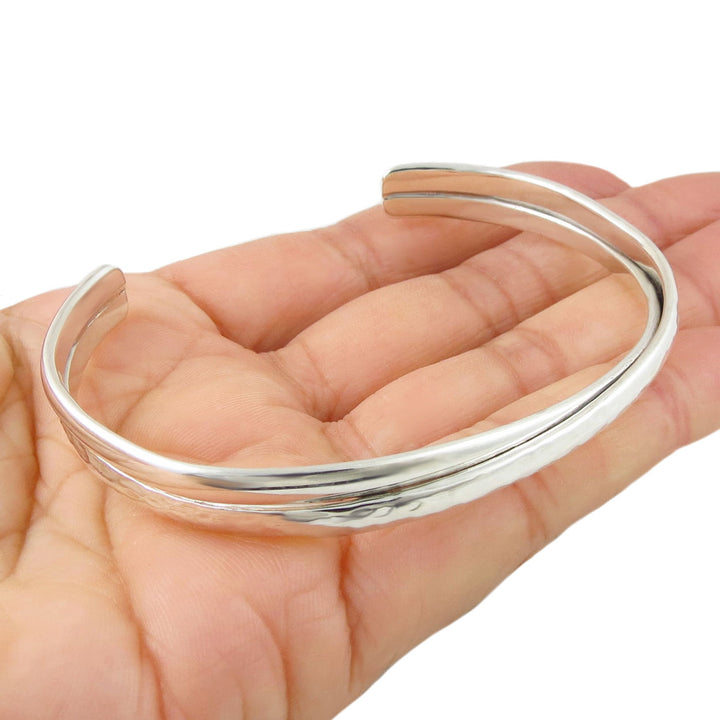 Sterling 925 silver bracelet for women with a hammered and polished finish held in a person's hand. 