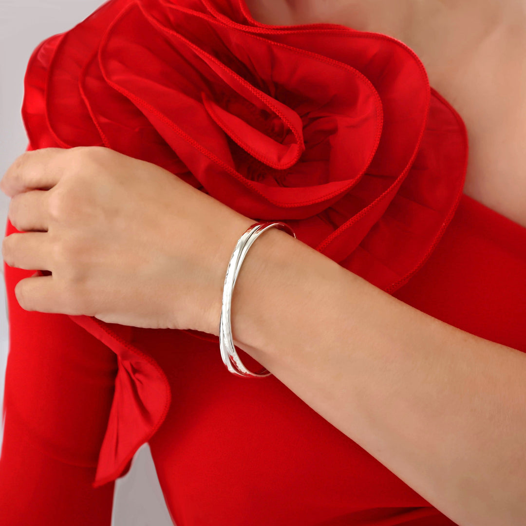 A double sterling silver twisted bracelet worn by a woman with a red dress and a large floral detail.