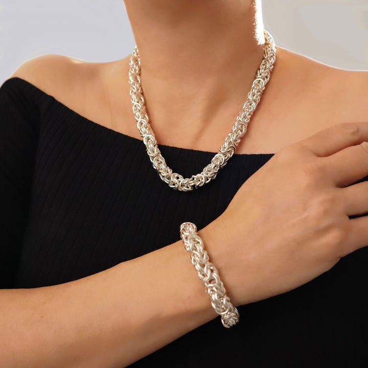 Sterling 925 Silver chunky byzantine chain necklace and matching bracelet on a woman against a light gray background