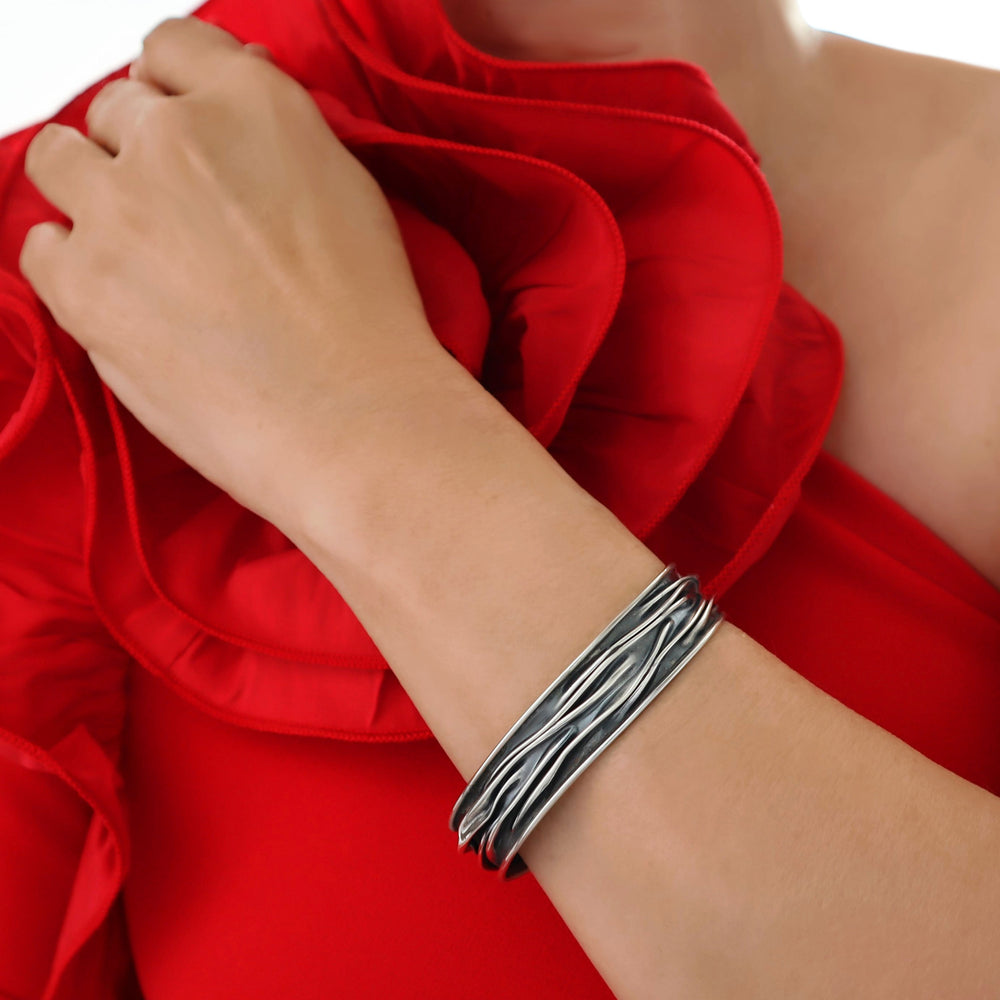 sterling silver handmade bracelet on a wrist with a red fabric background