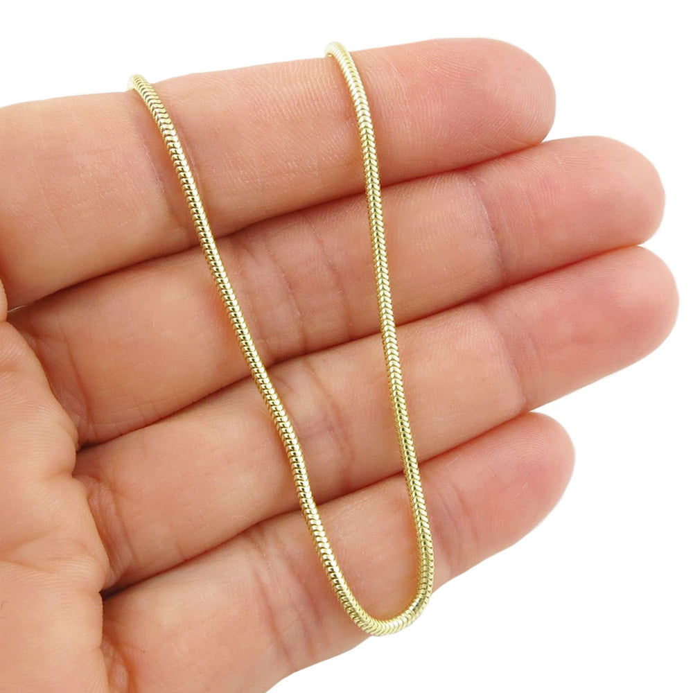 14ct gold chain snake bracelet held between fingers on a white background