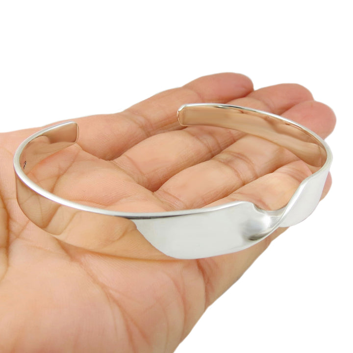 Large 925 sterling silver bracelet with a spiral detail at the front on a hand against a white background
