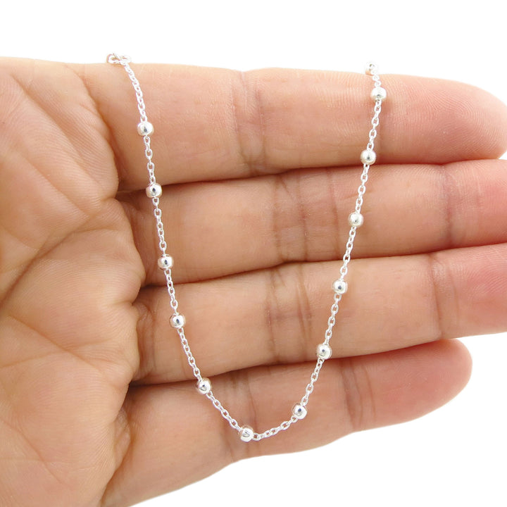 UK 925 silver chain bracelet with beaded links held in a hand against a white background