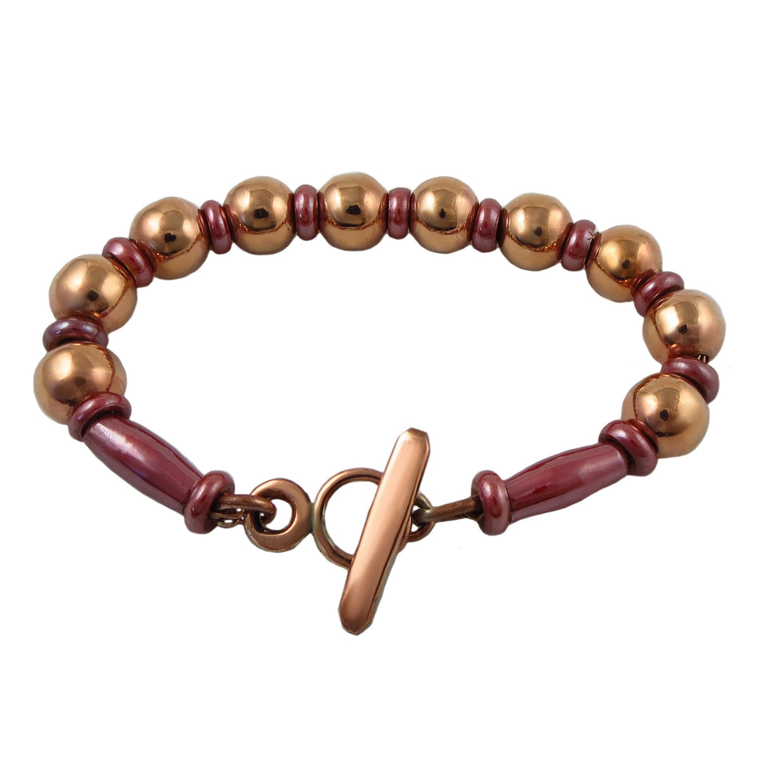 Bracelet for women with copper ball beads and rose pink spacers on a white background