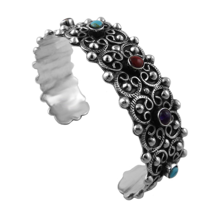 A heavy UK hallmarked 925 sterling silver cuff bracelet with intricate filigree scrollwork and small bezel-set multicolour turquoise, amethyst and coral red stones, shown on a plain white background.