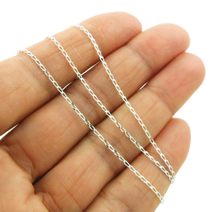 925 Silver curb chain necklace held between fingers on a white background