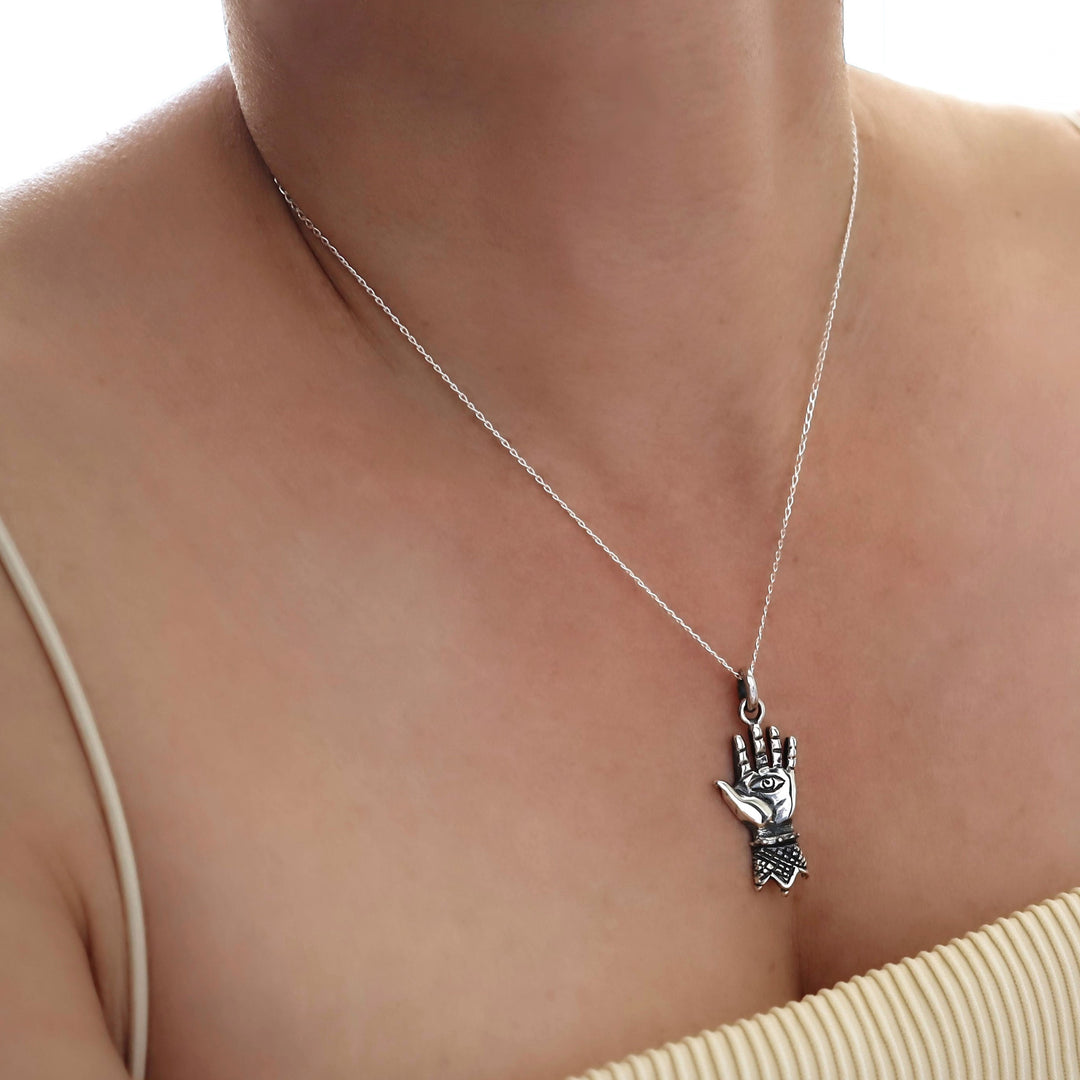 Silver curb chian necklace with a hand-shaped pendant on a person's neck