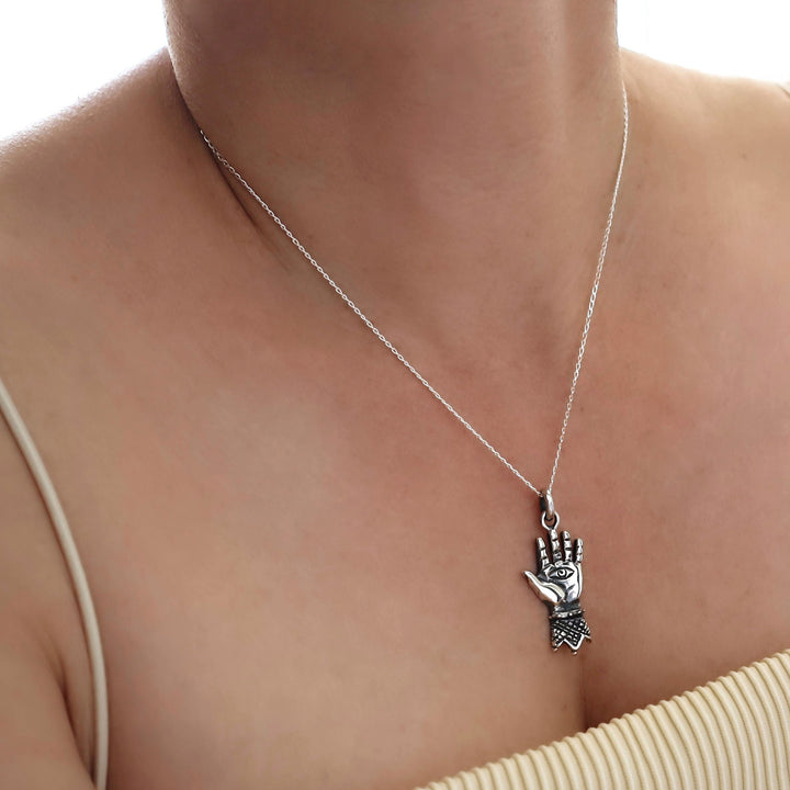 Silver curb chian necklace with a hand-shaped pendant on a person's neck