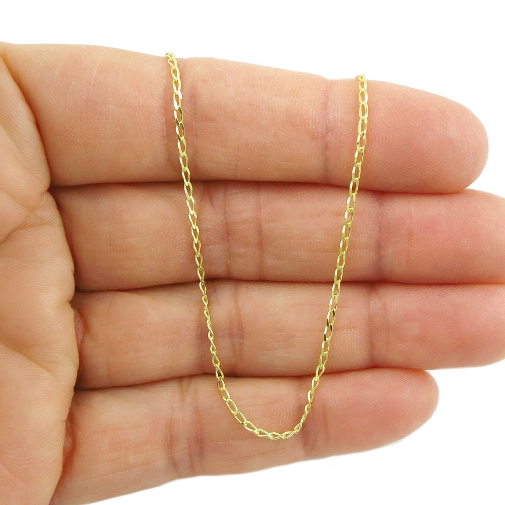 Gold curb chain held between fingers on a white background