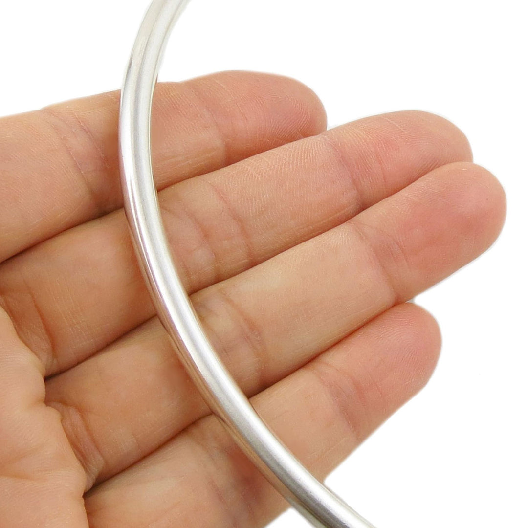 Silver slider tube choker held in a hand against a white background