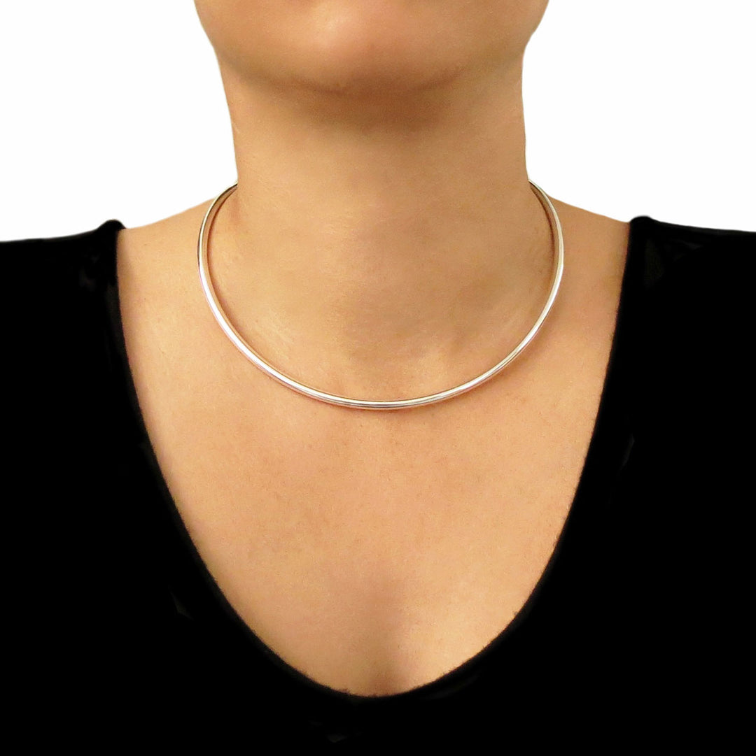 925 silver choker torque on a person wearing a black top against a white background