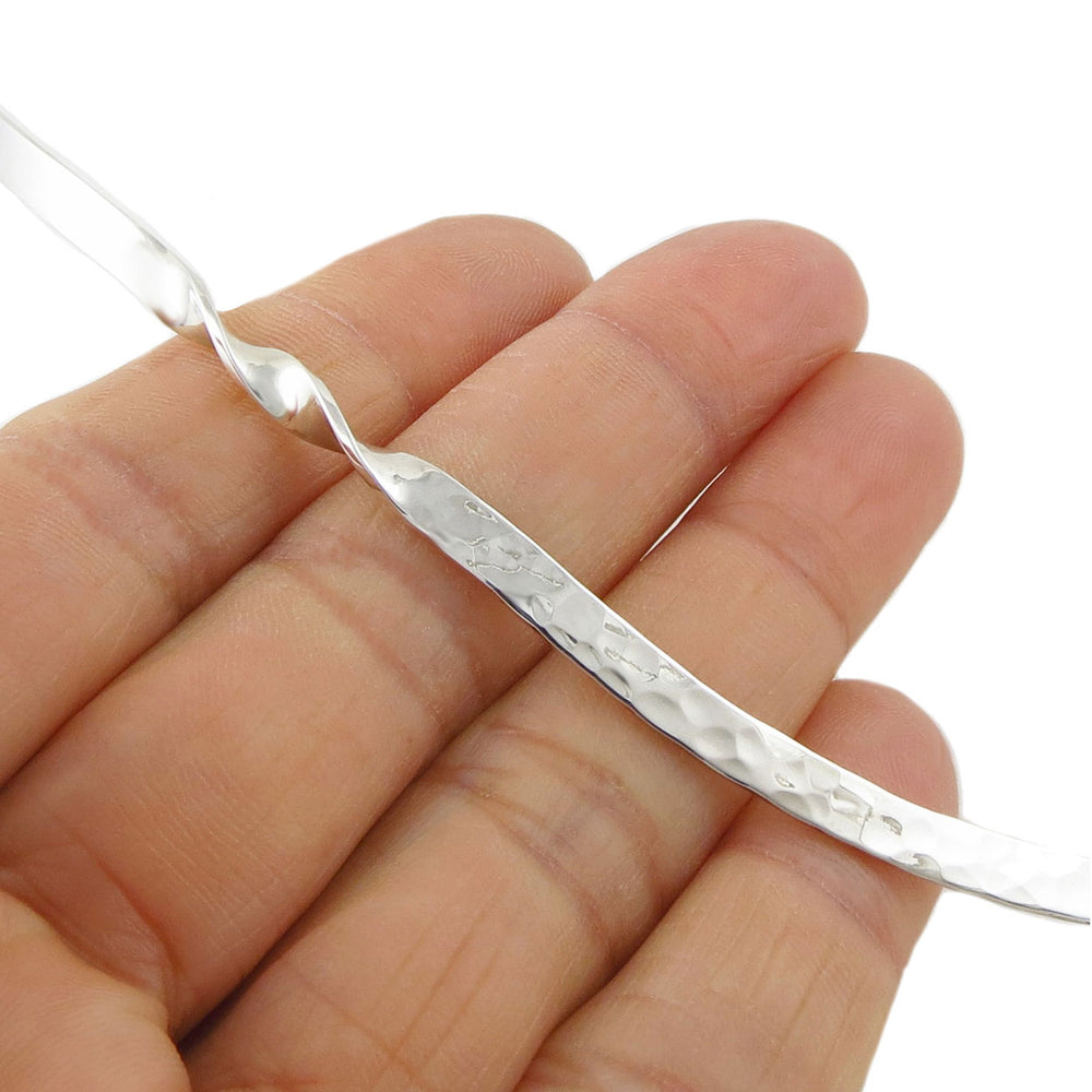 925 silver necklace torc being held between fingers on a white background