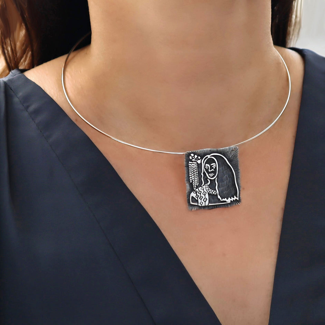 Wire choker necklace with a unique pendant featuring a stylized face design on a plain background