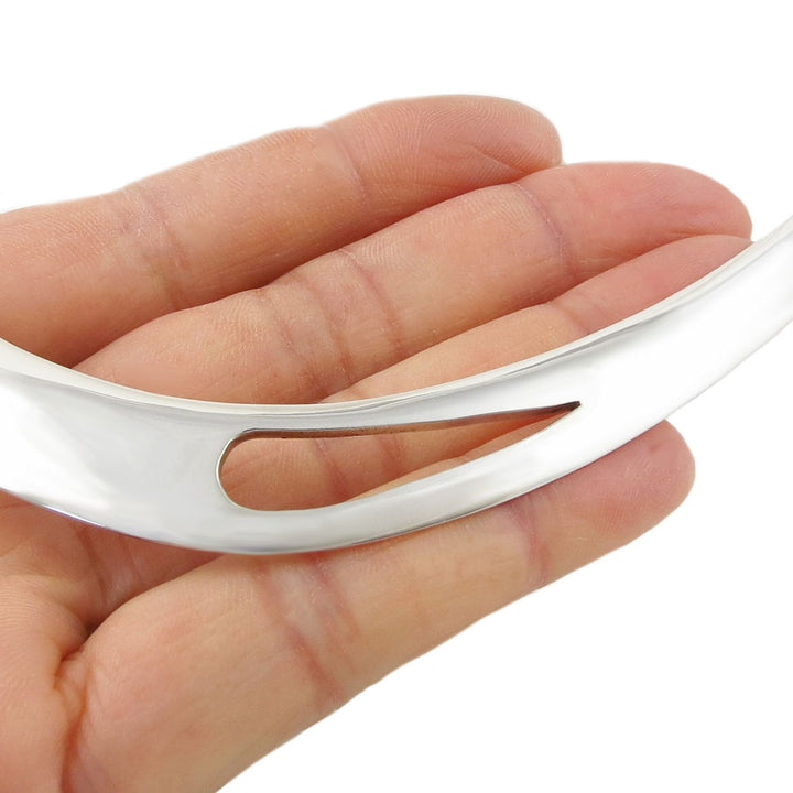 Silver choker necklace held in a hand against a white background