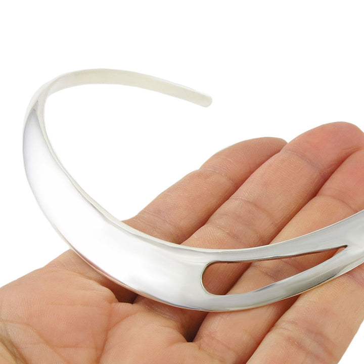 sterling silver choker necklace held in a hand against a white background
