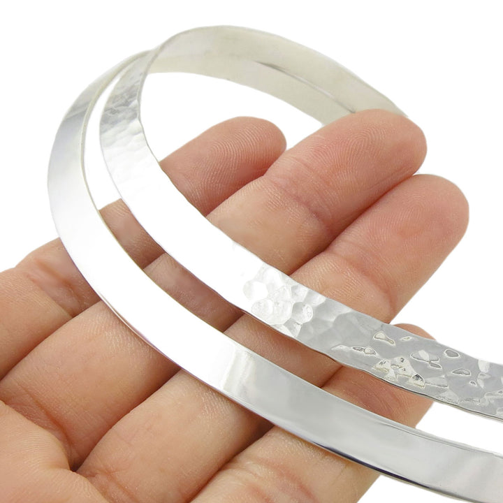 Wide double silver choker held in a hand against a white background