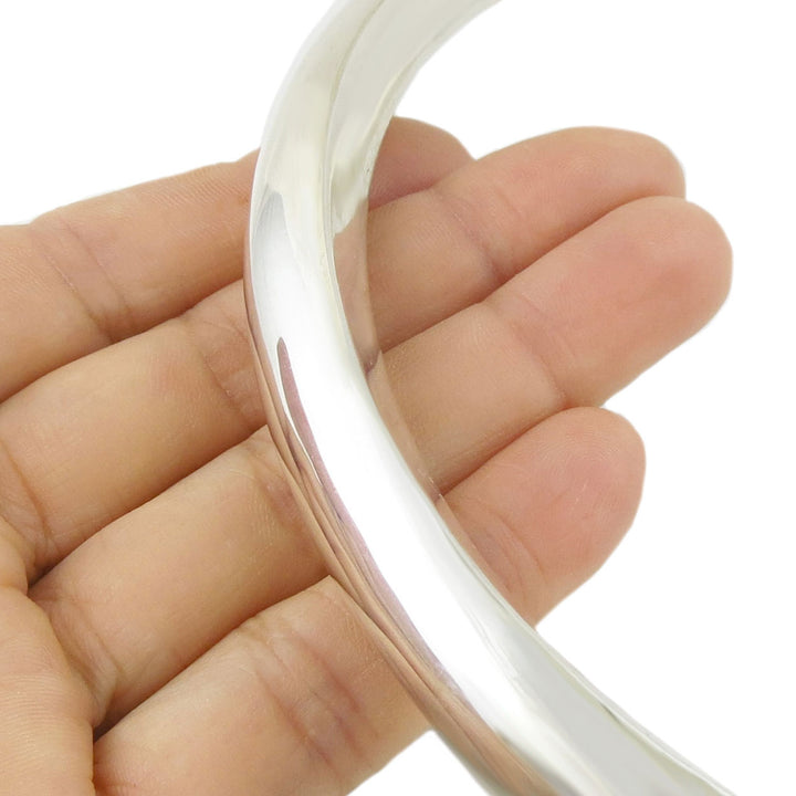 Rigid sterling 925 silver choker torc held in a woman's hand against a white background