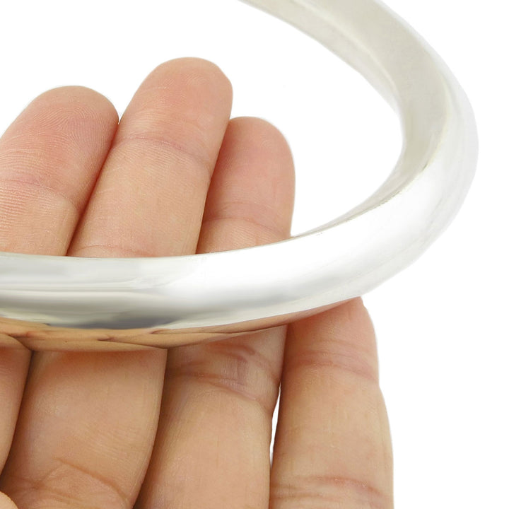 Chunky sterling 925 silver choker necklaace torc for women being held by a hand on a white background