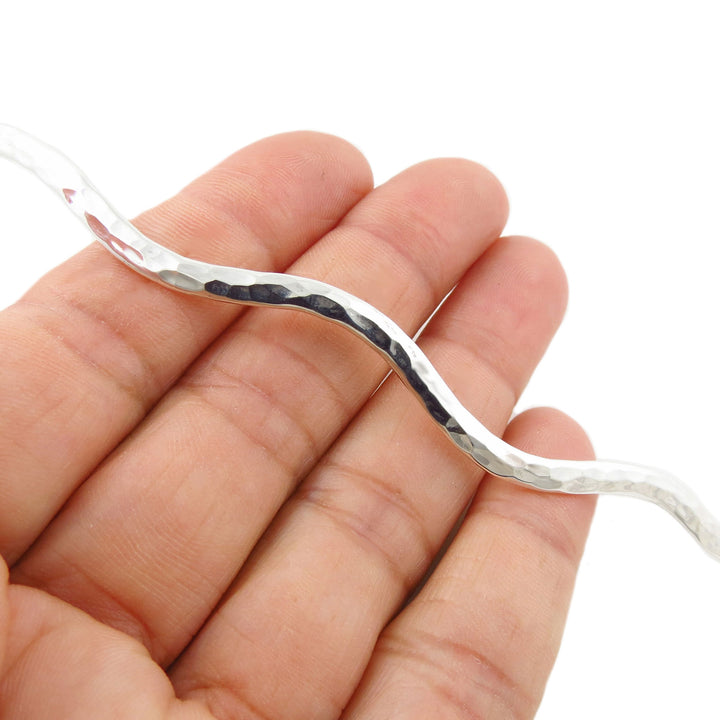 A close-up of a hand holding a hammered UK hallmarked 925 sterling silver choker necklace against a plain white background.