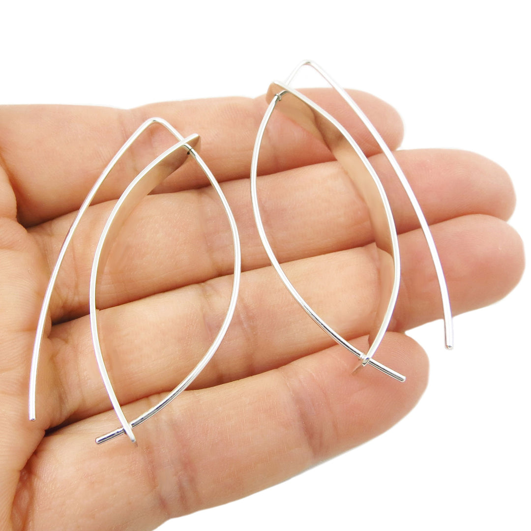 A pair of unusual silver hoop threader style earrings held between fingers on a white background