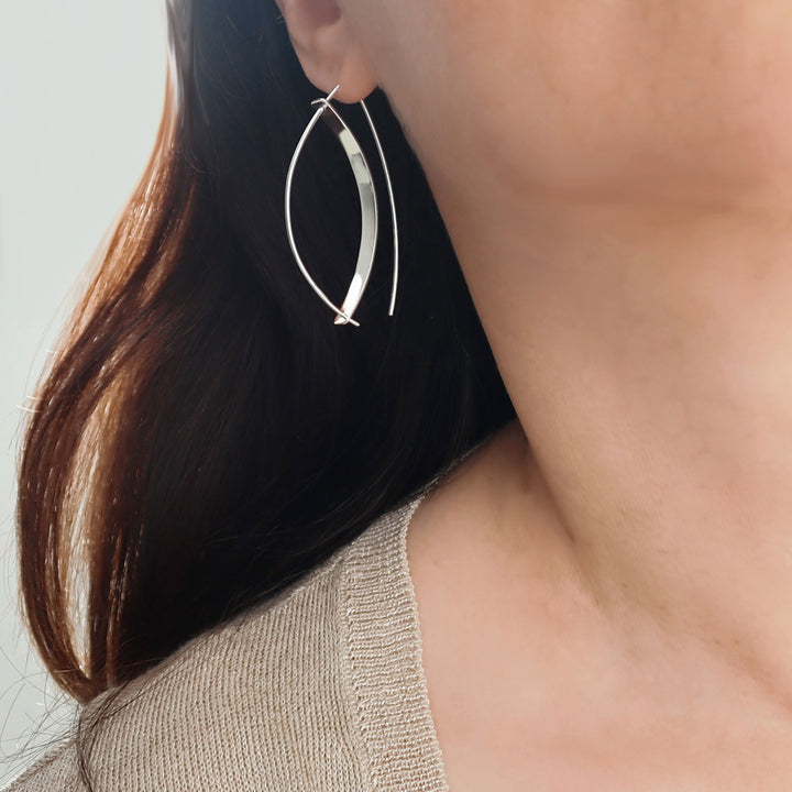 Close-up of a woman wearing Taxco solid 925 silver hoop earrings with a neutral background